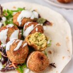 falafel balls in on a bed of salad and tortilla wrap.