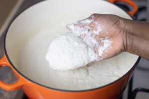 a hand with touching white paste in the pot.