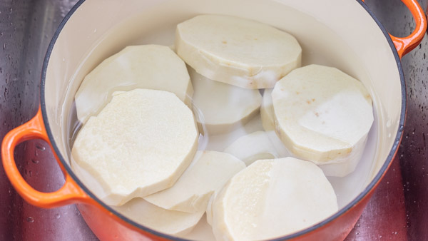 yam slices in a in a pot covered with water.